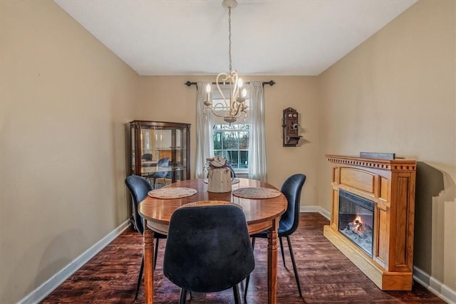 dining space featuring dark wood-style floors, a glass covered fireplace, a notable chandelier, and baseboards