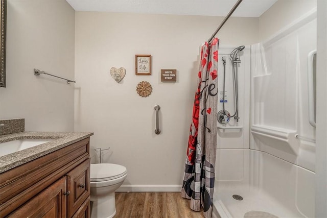 full bath featuring wood finished floors, a shower stall, vanity, and baseboards