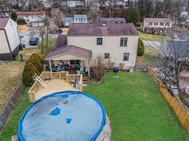 rear view of property with a fenced backyard, a wooden deck, and a lawn