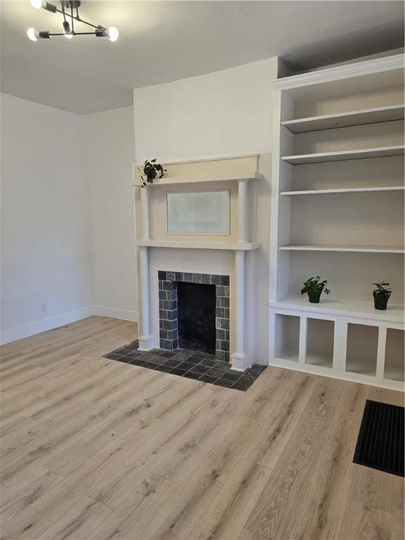 unfurnished living room featuring baseboards, wood finished floors, and a tile fireplace