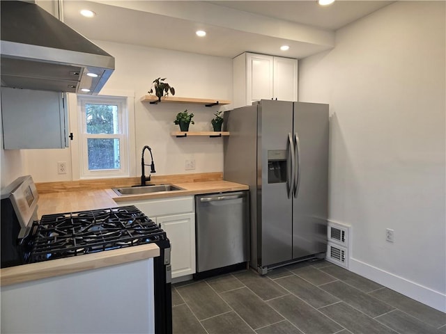 kitchen with stainless steel appliances, light countertops, white cabinetry, a sink, and exhaust hood