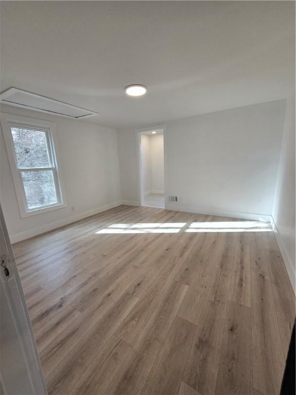 spare room featuring light wood-type flooring and baseboards