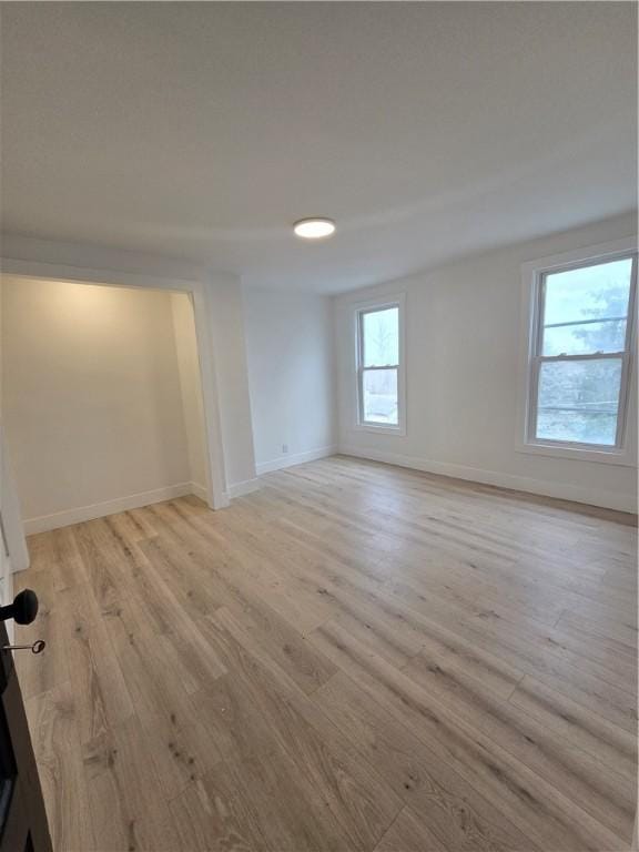 unfurnished room with light wood-style flooring and baseboards