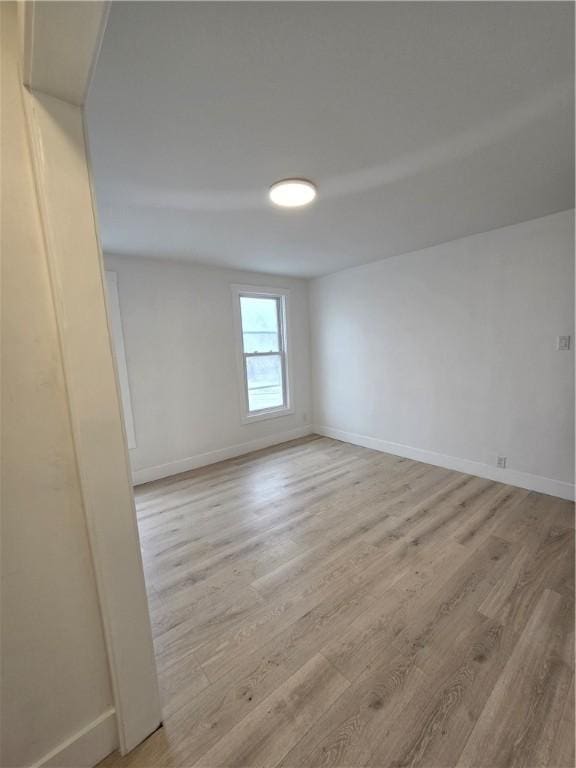 unfurnished room featuring baseboards and light wood-style floors