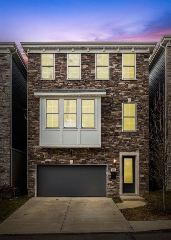 view of front of home with a garage, stone siding, and concrete driveway