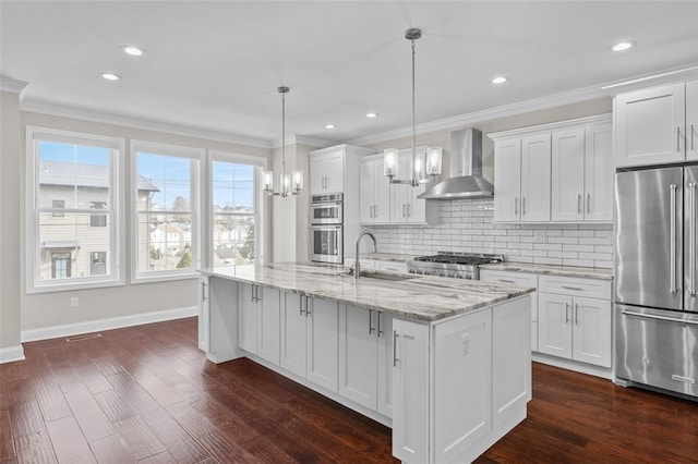 kitchen featuring stainless steel appliances, white cabinetry, a sink, and wall chimney exhaust hood