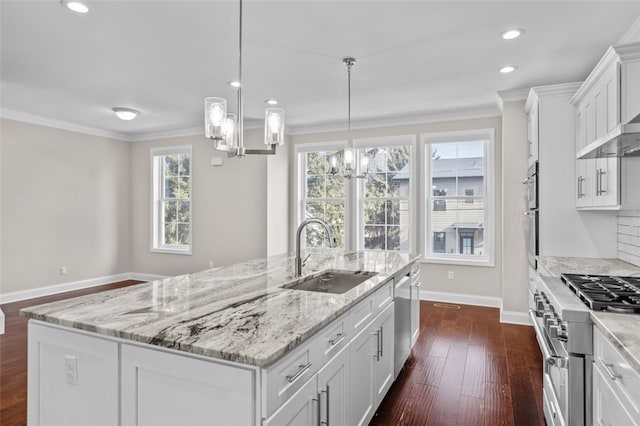 kitchen with stainless steel appliances, ornamental molding, a sink, and a kitchen island with sink