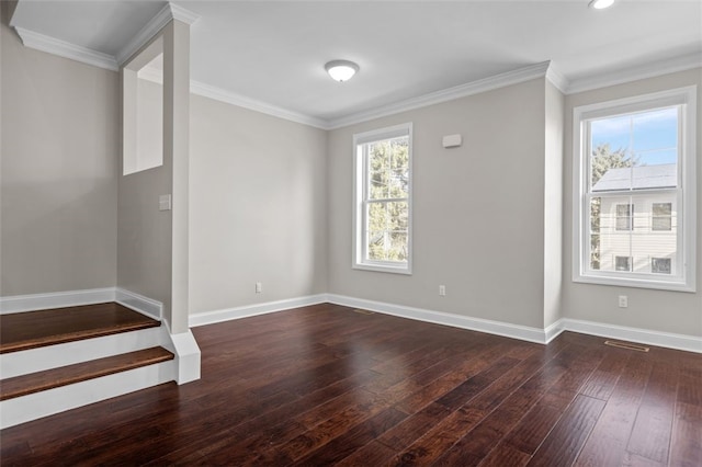 empty room featuring baseboards, ornamental molding, and dark wood finished floors