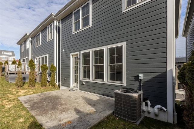 rear view of house featuring a patio area, central AC, and a lawn