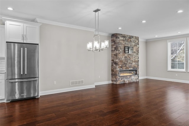 unfurnished living room featuring visible vents, dark wood-type flooring, ornamental molding, a stone fireplace, and baseboards