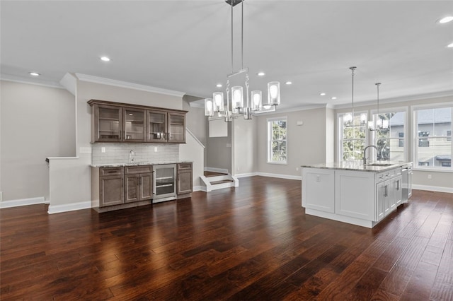 kitchen with beverage cooler, a sink, tasteful backsplash, dark wood finished floors, and glass insert cabinets