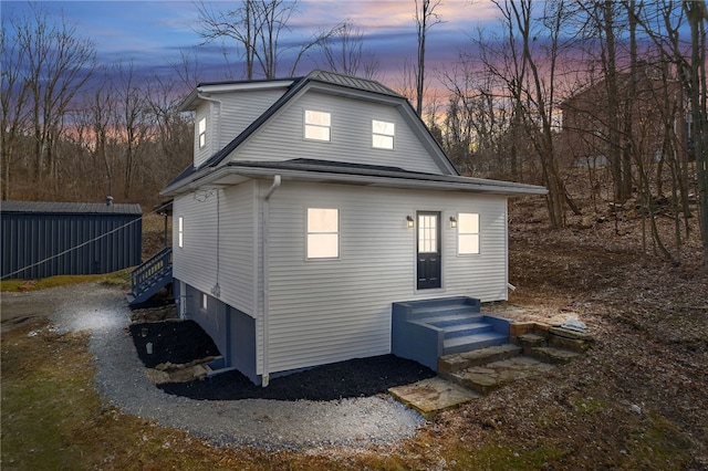 property exterior at dusk with driveway and a gambrel roof