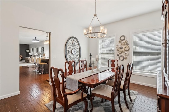 dining space featuring baseboards, wood-type flooring, and a notable chandelier