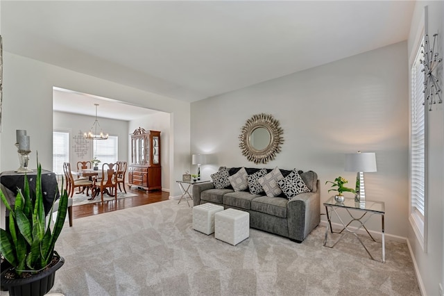 carpeted living area featuring baseboards and an inviting chandelier