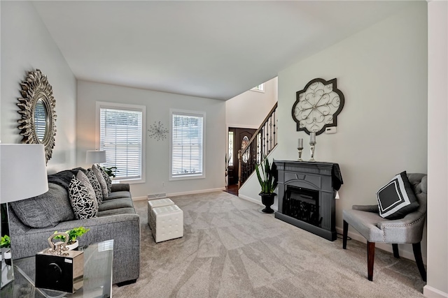 carpeted living area featuring stairway, a fireplace, visible vents, and baseboards