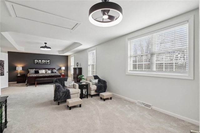 sitting room featuring carpet floors, a tray ceiling, visible vents, attic access, and baseboards