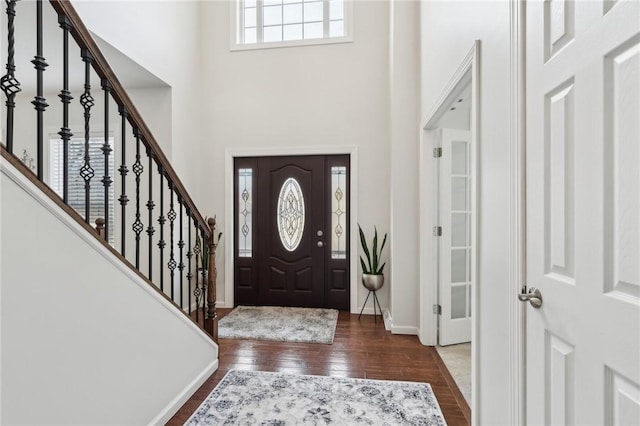 entrance foyer with a towering ceiling, stairs, baseboards, and dark wood-style flooring