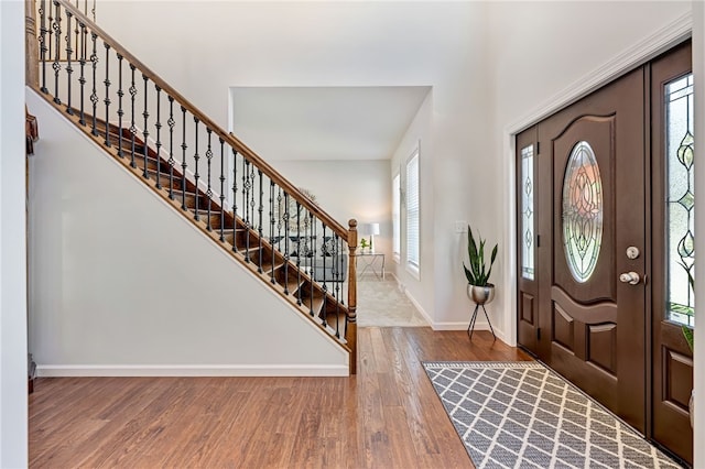 foyer with stairway, wood finished floors, and baseboards