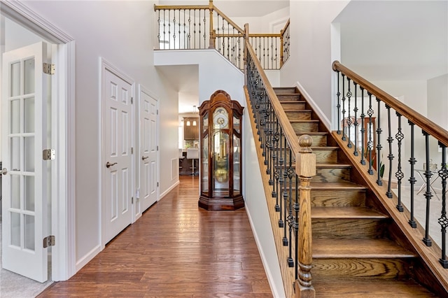 stairway with a high ceiling, baseboards, and wood finished floors