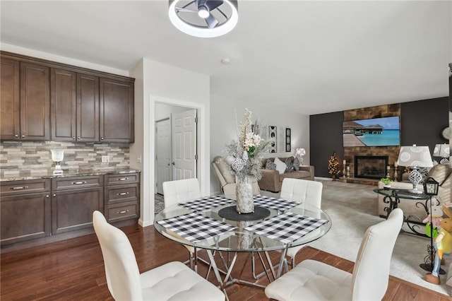 dining area with dark wood-style floors and a large fireplace