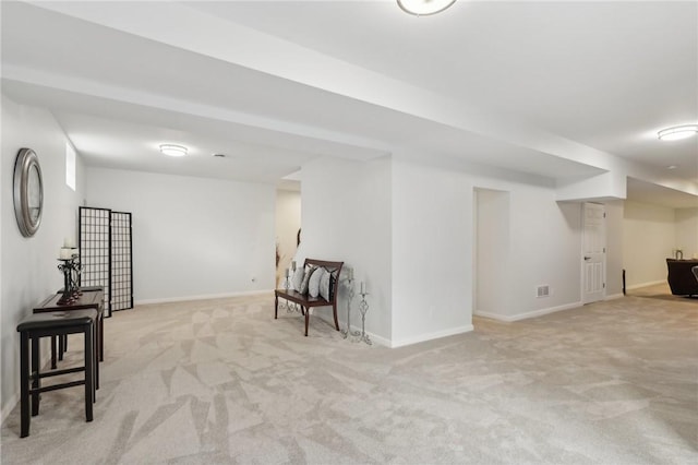 finished basement with visible vents, baseboards, and light colored carpet