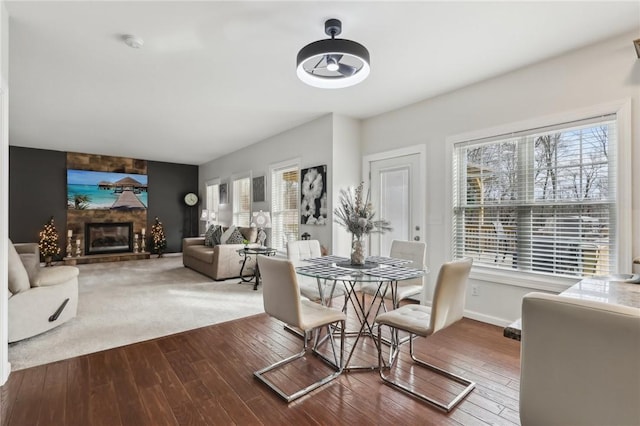 dining space featuring a large fireplace, baseboards, and hardwood / wood-style floors