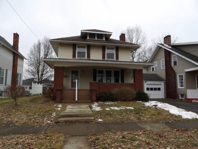 american foursquare style home with an outbuilding, a porch, aphalt driveway, a garage, and brick siding