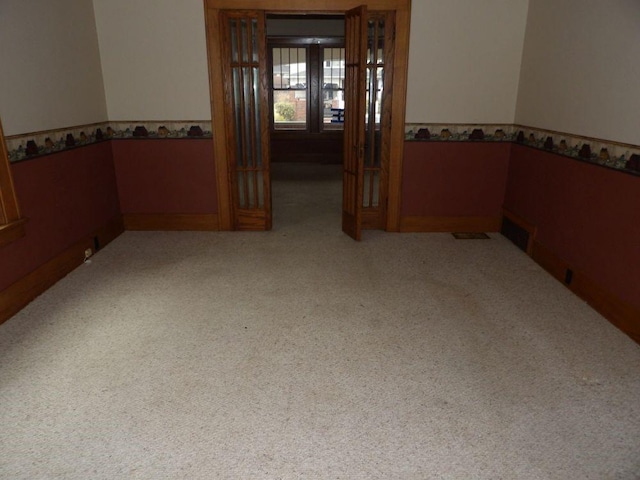 carpeted empty room featuring a wainscoted wall and visible vents