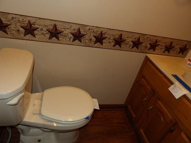 half bath with toilet, baseboards, and wood finished floors