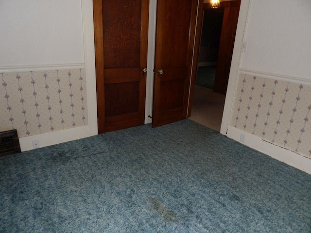 spare room featuring a wainscoted wall, carpet flooring, and wallpapered walls