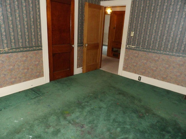 carpeted spare room with baseboards and wallpapered walls