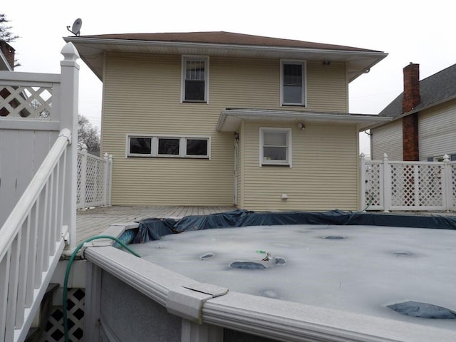 back of house with a hot tub and fence