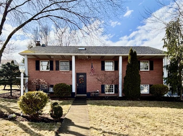 split foyer home featuring a front yard and brick siding