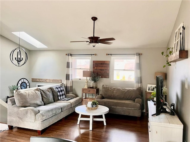 living area with lofted ceiling with skylight, dark wood finished floors, and ceiling fan with notable chandelier