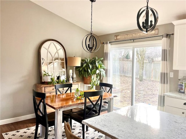 dining area featuring dark wood-style floors, vaulted ceiling, and baseboards