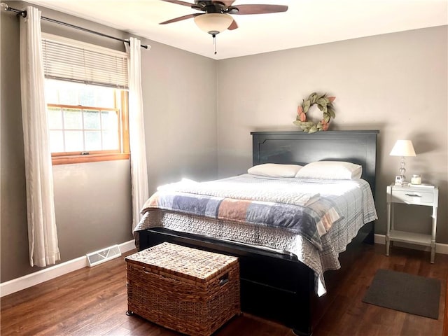 bedroom with a ceiling fan, visible vents, baseboards, and wood finished floors