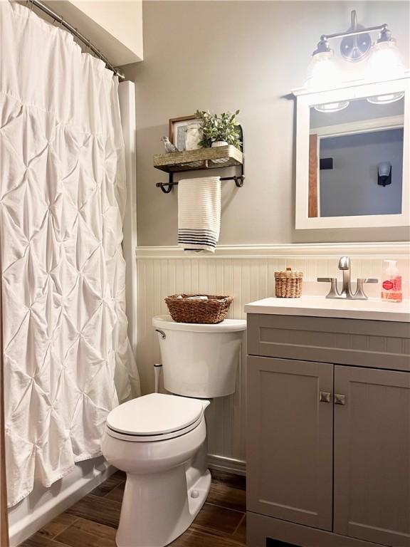 bathroom with vanity, wainscoting, wood finished floors, and toilet