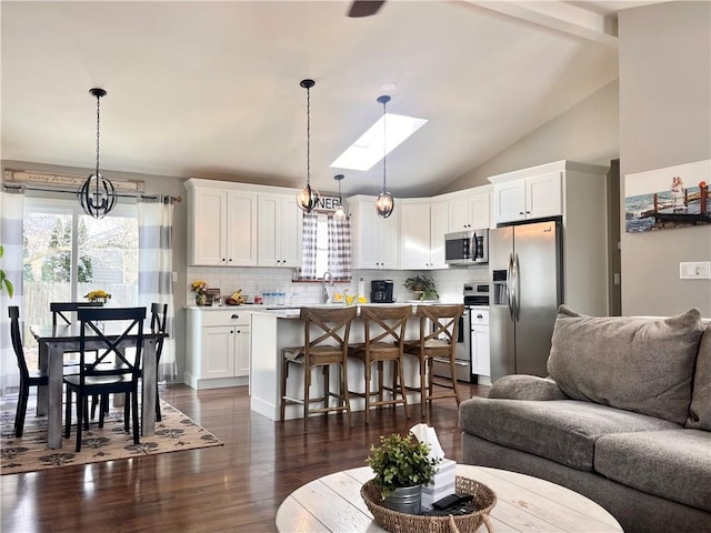 living room featuring dark wood-style floors, vaulted ceiling with skylight, and plenty of natural light