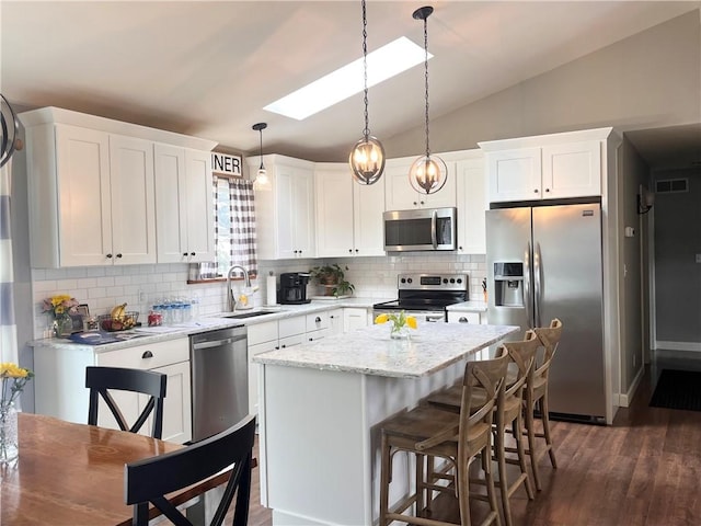 kitchen with stainless steel appliances, visible vents, lofted ceiling with skylight, white cabinets, and a sink