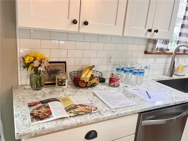 kitchen with white cabinets, a sink, backsplash, and stainless steel dishwasher