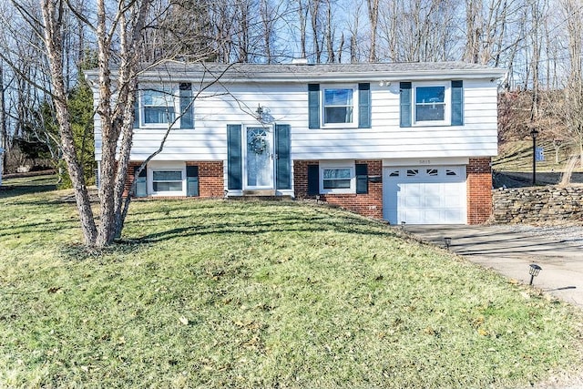 bi-level home featuring a garage, brick siding, driveway, and a front lawn