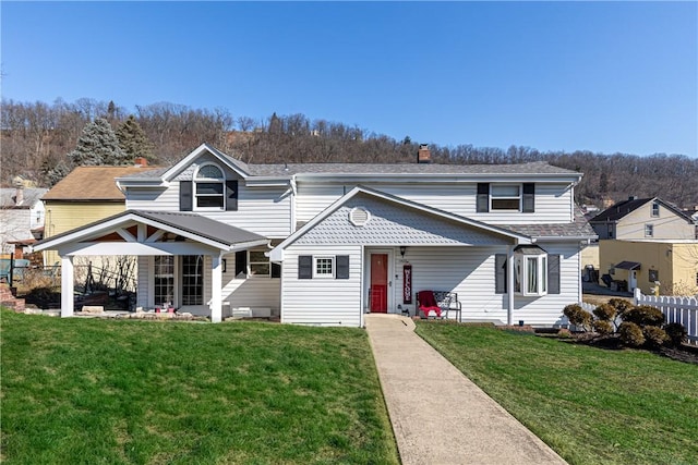 traditional-style home with a front yard, fence, and a chimney