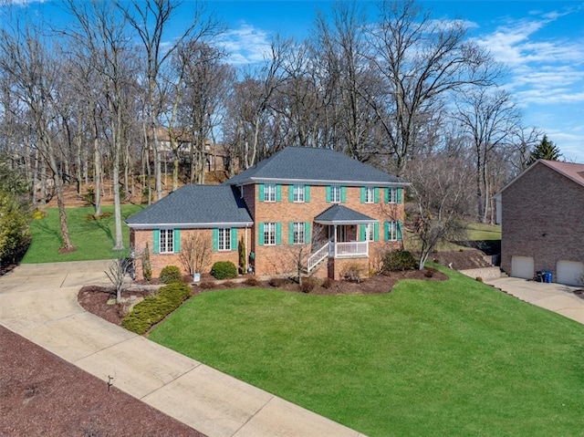 view of front of property featuring covered porch, brick siding, concrete driveway, and a front yard