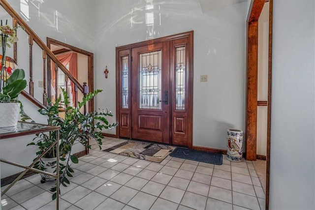 entryway with light tile patterned floors, stairs, and baseboards