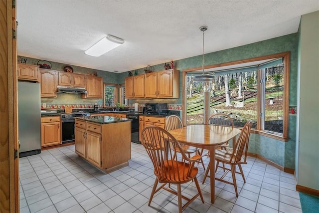 kitchen with dark countertops, a kitchen island, a textured ceiling, under cabinet range hood, and black appliances