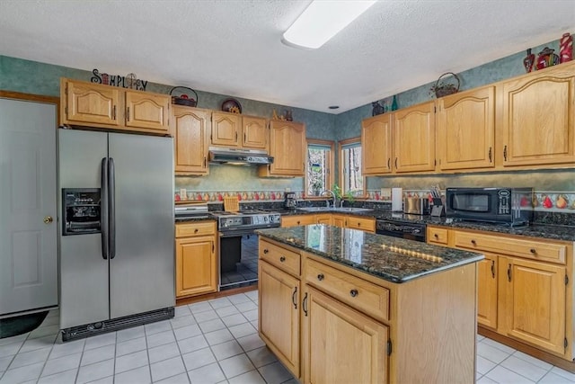 kitchen with a center island, light tile patterned floors, dark stone counters, under cabinet range hood, and black appliances