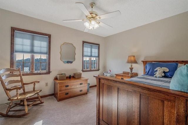 bedroom with light carpet, ceiling fan, multiple windows, and baseboards