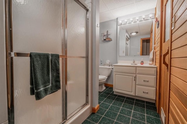 full bathroom featuring a drop ceiling, toilet, tile patterned floors, vanity, and a shower stall