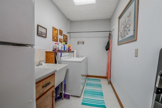 laundry area with laundry area, baseboards, a sink, and independent washer and dryer