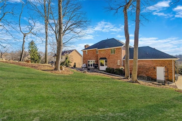 back of property with brick siding, a chimney, and a lawn